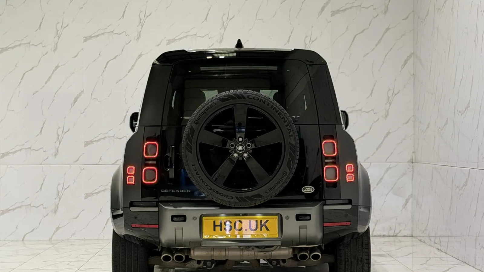 2022 Land Rover Defender 110 — Rear view showing the side-hinged door and mounted spare wheel