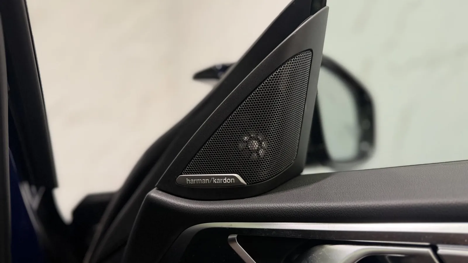 2023 BMW i4 — Close view of a Harman Kardon speaker grille in the door mirror sail panel