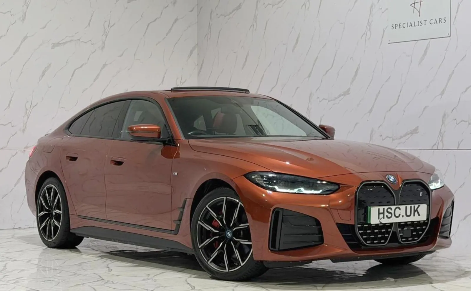 2023 BMW i4 — Front three-quarter view of the orange i4 on the showroom floor