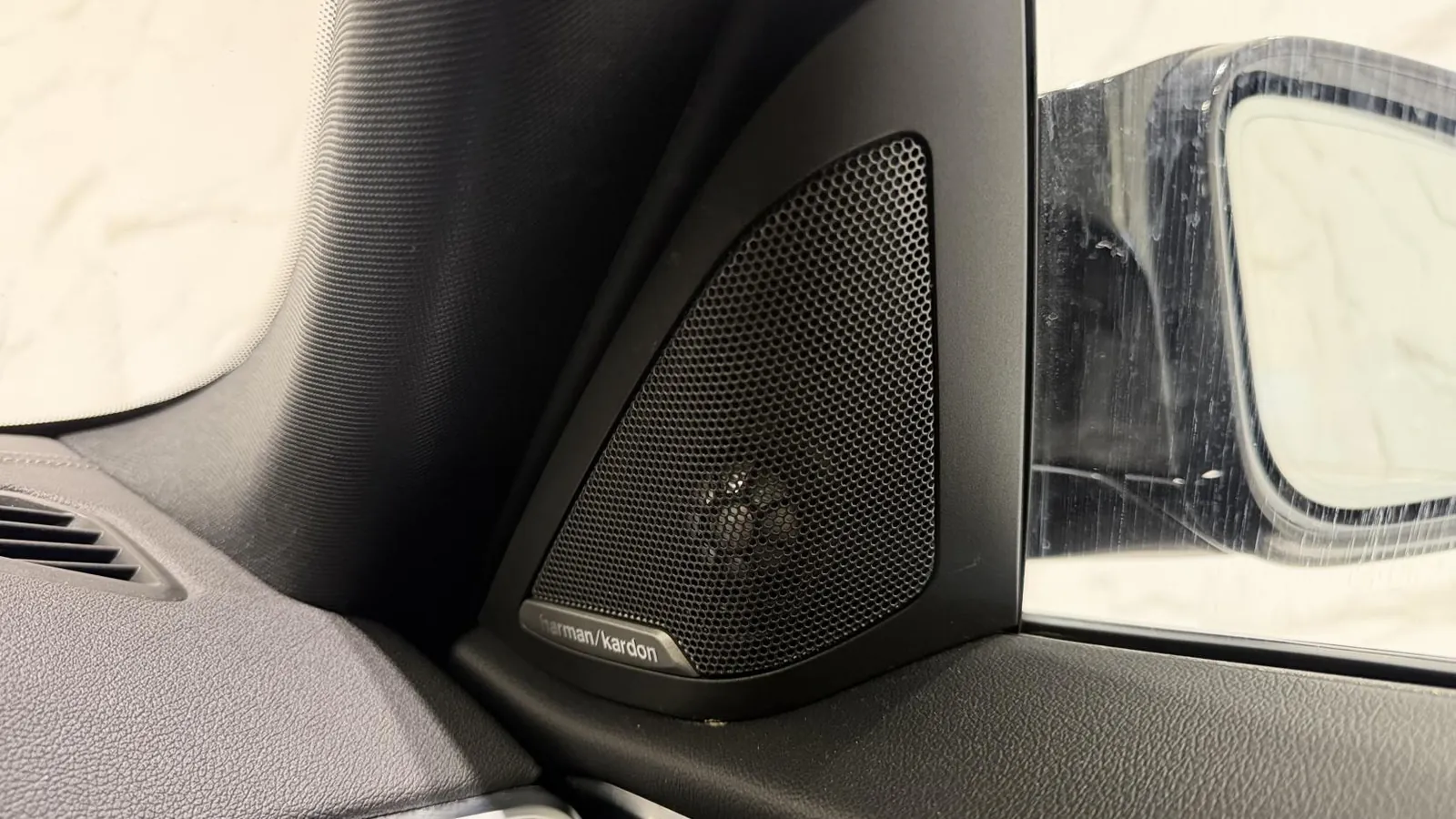 2023 BMW i4 — Close view of a Harman Kardon speaker grille in the door mirror sail panel